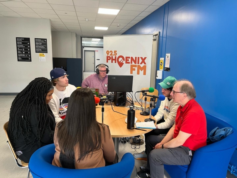 6 people around a table doing an outside broadcast for Phoenix FM